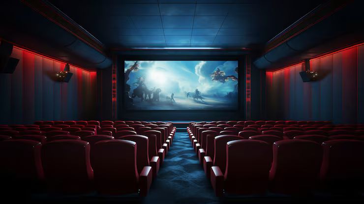Sala de cinema com poltronas vermelhas e tela acesa